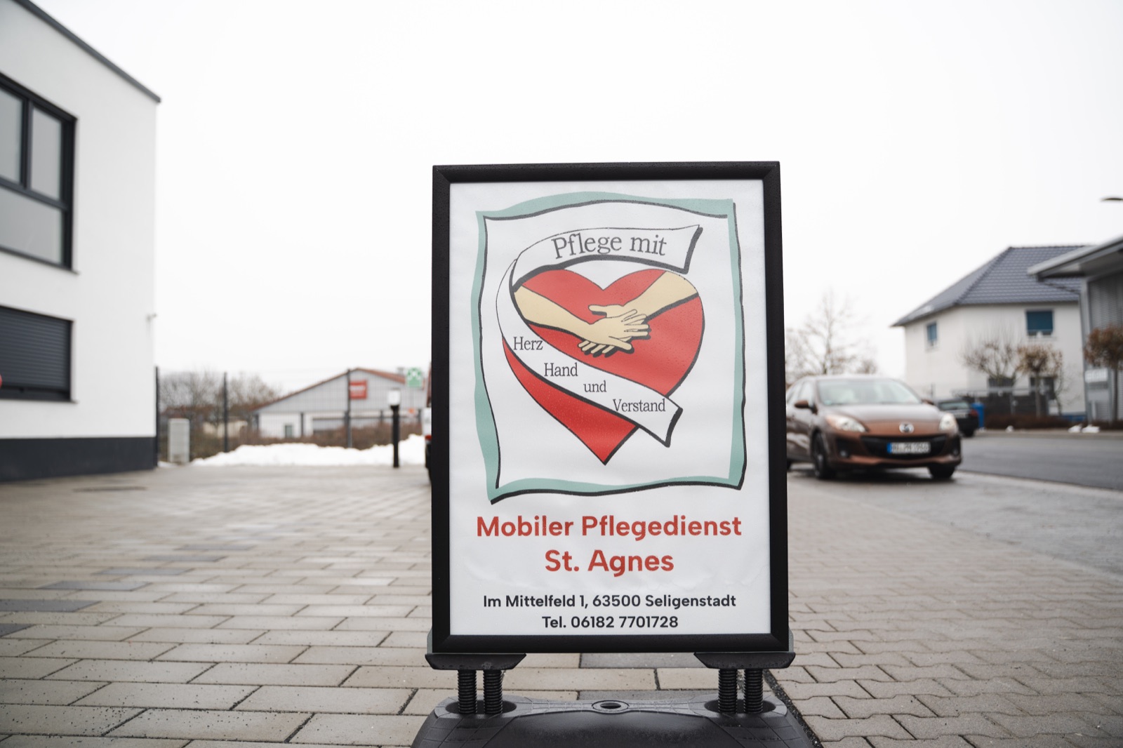 Schild des Mobilen Pflegedienst St. Agnes mit dem Leitsatz 'Pflege mit Herz, Hand und Verstand', Im Mittelfeld 1 in Seligenstadt